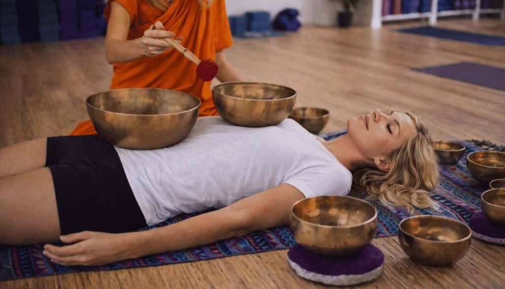 Immagine che illustra una seduta di bagni di suoni con le campane tibetane posizionate anche sul corpo del paziente