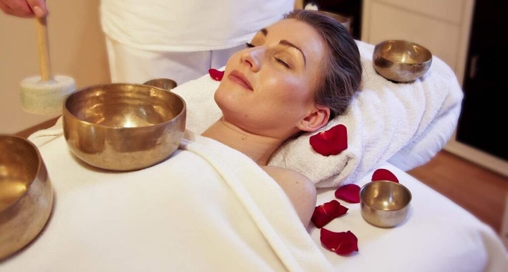 Immagine che illustra una seduta di bagni di suoni con una campana tibetana posizionata anche sul corpo della paziente